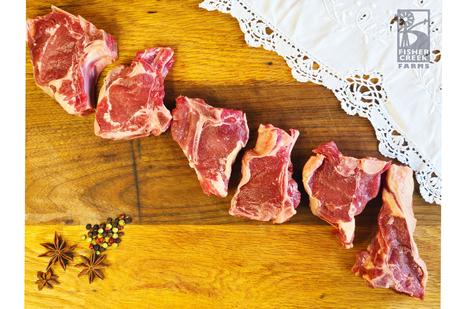 Goat chops on a wooden cutting board with a lace cloth and spices.